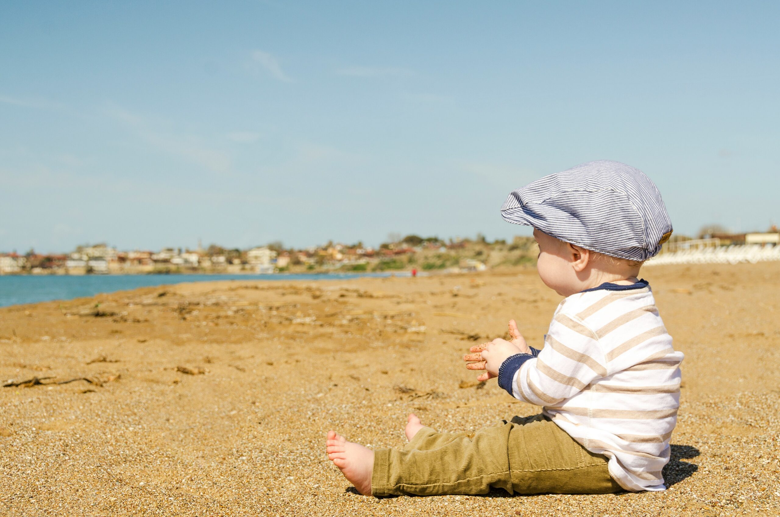a child sitting on the ground, along the beach. The Role of DCPP in Adoption Cases.