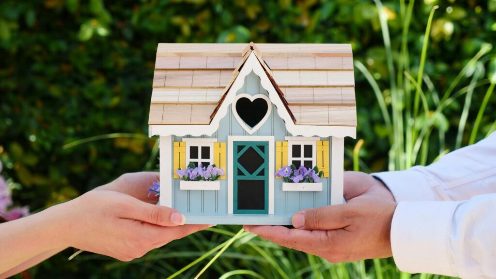 Two people holding a miniature wooden house, representing the division of real estate holdings in a New Jersey high-asset divorce